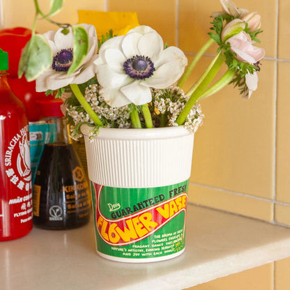 Flower vase with flowers on a kitchen shelf next to condiments