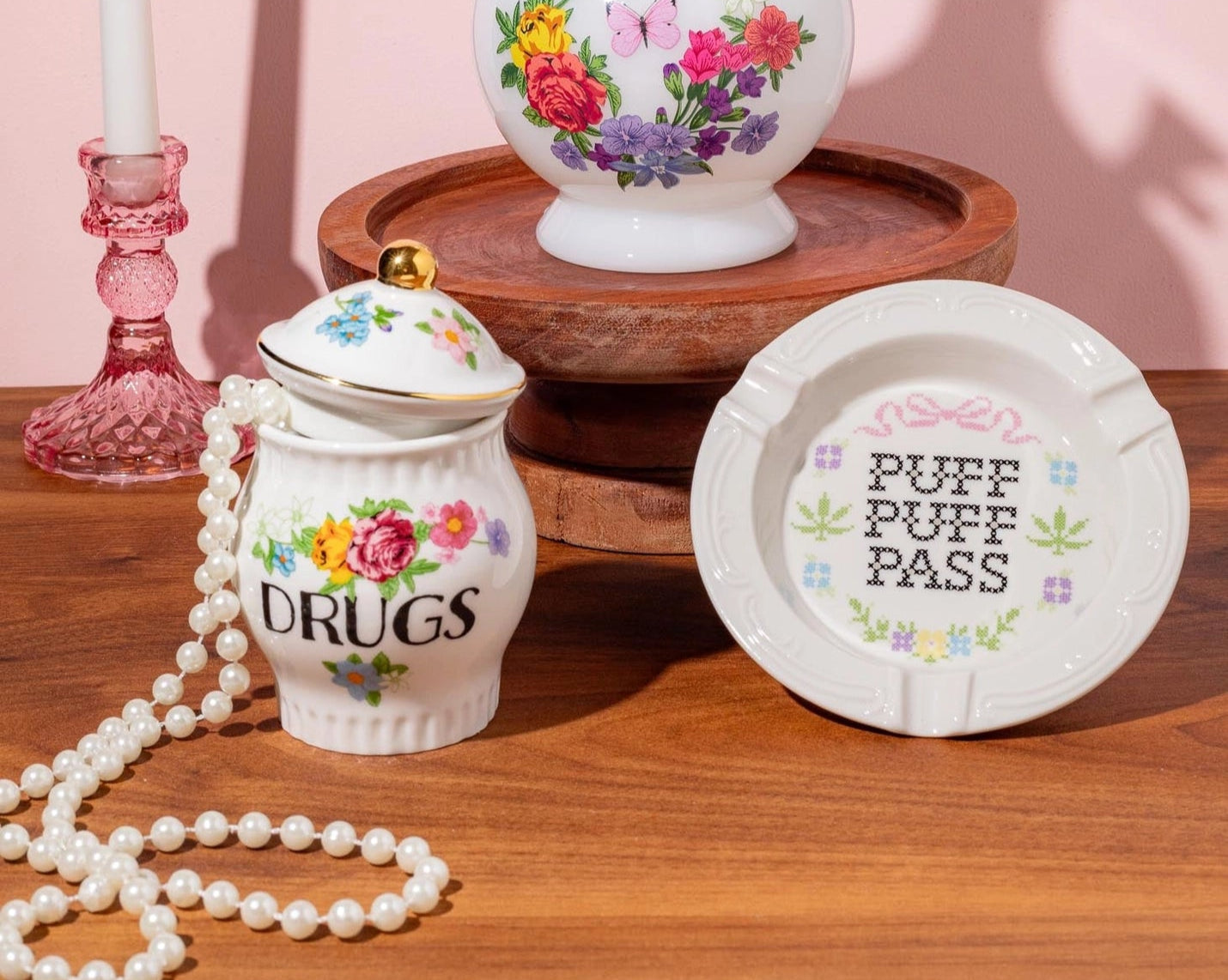 Decorative items including a vase, jar, and plate with floral designs on a wooden surface.